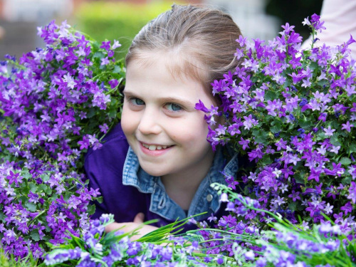 A girl smiling surrounded by flowers